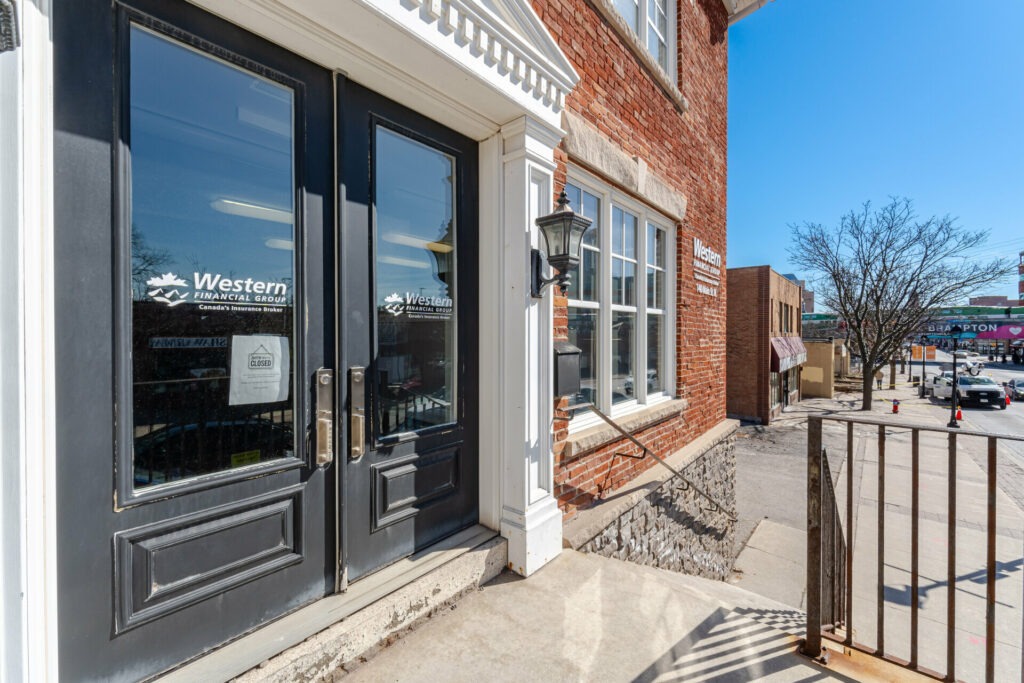 Entrance of Western Financial Group, featuring dark double doors with a closed sign, brick building exterior, and clear blue sky.