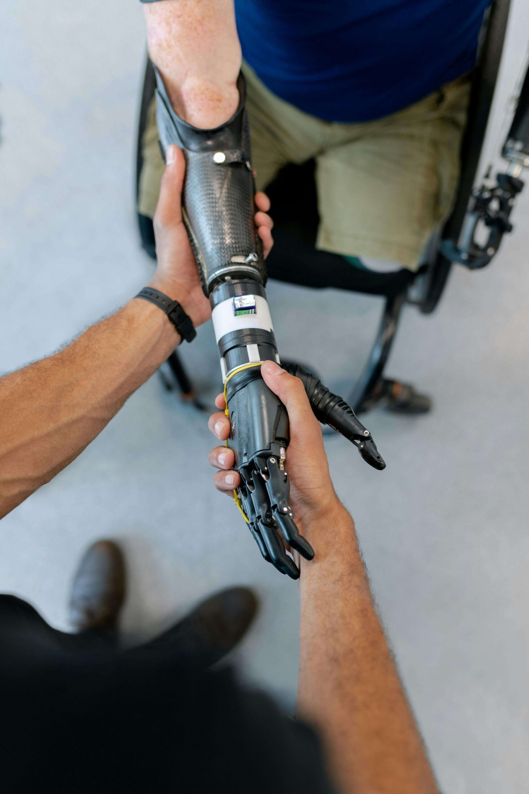 A person with a prosthetic arm holds hands with another, showcasing advanced robotic technology in assistive devices and rehabilitation.