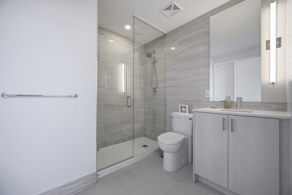 Modern bathroom featuring a glass shower, sleek cabinetry, and neutral gray tones. The design emphasizes cleanliness and functionality.