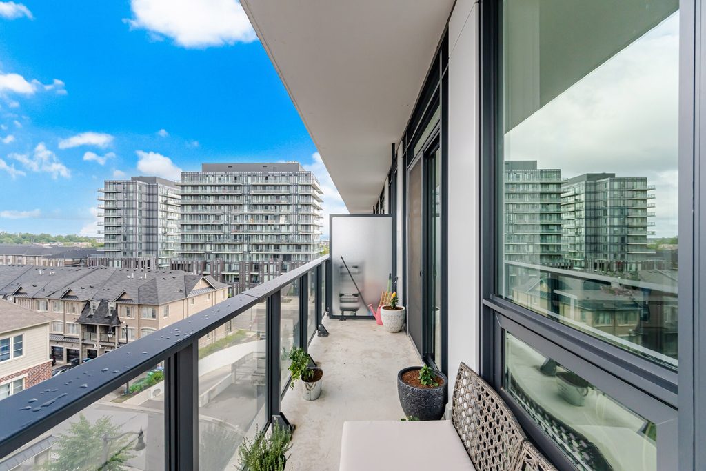 Balcony view showcasing modern high-rise buildings against a bright blue sky, with planters and seating adding a touch of home comfort.