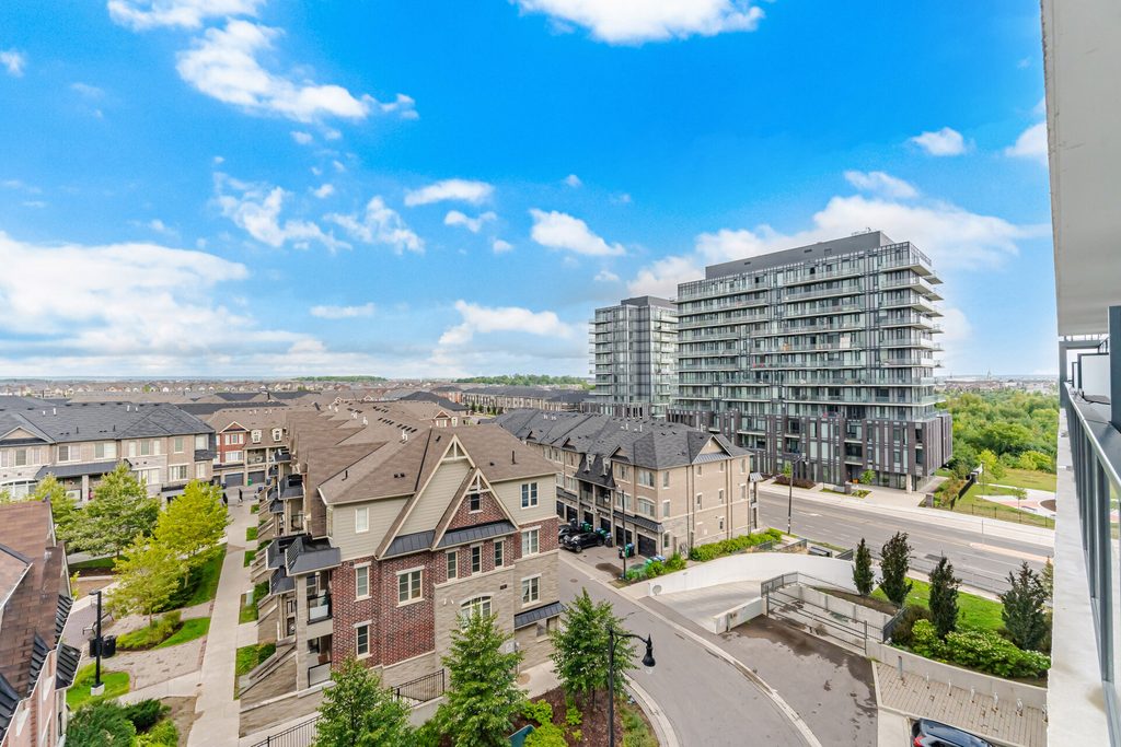 Aerial view of a suburban area featuring modern buildings and traditional homes, with clear blue skies and greenery, showcasing urban development.
