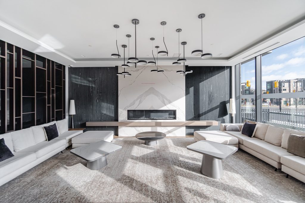 Modern living room featuring a minimalist design with a marble fireplace, sleek furniture, and ample natural light from large windows.
