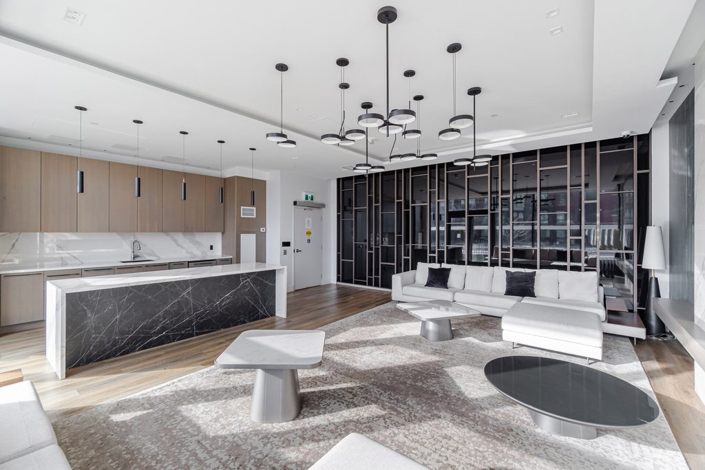 Modern living room with an open kitchen featuring a marble island, sleek furniture, and contemporary lighting, showcasing a stylish interior design.